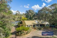  240 Iron Rd Parkerville WA 6081 $990,000 A long, paved driveway winds through a natural landscape to the valley floor and a magical realm hidden from the world. Tree ferns, azaleas and hydrangeas thrive in a shady glen, masses of roses create a perfumed paradise, Jane Brook meanders around and across the 8-acre property, and the large family home looks out to a natural amphitheatre set against a backdrop of tall gums. It’s not only the sense of seclusion that gives this tightly held, Parkerville property an otherworldly atmosphere. 5 bedrooms 2 bathrooms OP family/kitchen/meals Formal lounge & dining High ceiling exposed beams Extensive outdoor living Enclosed below-ground pool Superb natural amphitheatre Jane Brook & Heritage Trail Enchanted 8-acre paradise Hidden minutes from town Touched by more than a sprinkling of fairy dust, this much-loved family property appears as a vision. Hidden away, yet within easy reach of services and amenities, this remarkable, bewitching site offers an unparalleled sense of seclusion and a front-row seat to the changing seasons with Jane Brook running during winter, a waterfall rushing over granite outcrops and much-loved and extensive gardens that include a grass meadow, old fruit trees and a gazebo shaded by wisteria and ringed with roses. The home’s quirky layout is in perfect keeping with its unique setting. It features multiple living areas, a loft, large bedrooms and a central open plan with a high ceiling and exposed beams. The opportunity to gently coax the property back to its former glory is a worthy quest with rich rewards. There is ample scope and amenity to live comfortably while undertaking this transformation. Bedrooms and bathrooms are arranged on either side of the shared living zones, with the high-ceilinged open plan forming the heart of the layout. An electric fire, working potbelly, exposed beams and dual-aspect glazing bring charm and comfort to this family hub. Brick-paved patios extend north and south of the home, with paths on one side winding around gardens to the pool and, on the other, an elevated view across the valley floor to the banks of the brook. To nurture and protect this magnificent piece of the Hills is a rare and unmatched prospect. To fashion a blue-ribbon property that stands at the centre of family life for generations is a once-in-a-lifetime opportunity. 